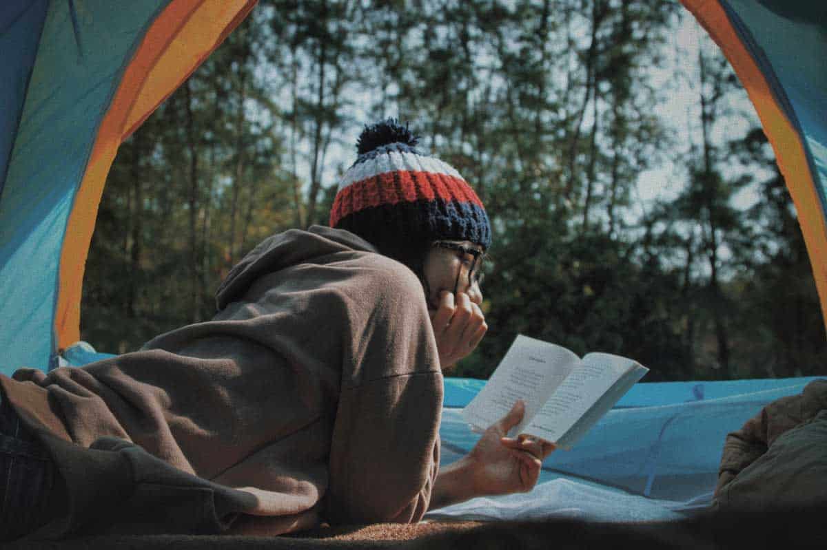 girl reads a book inside a camping tent