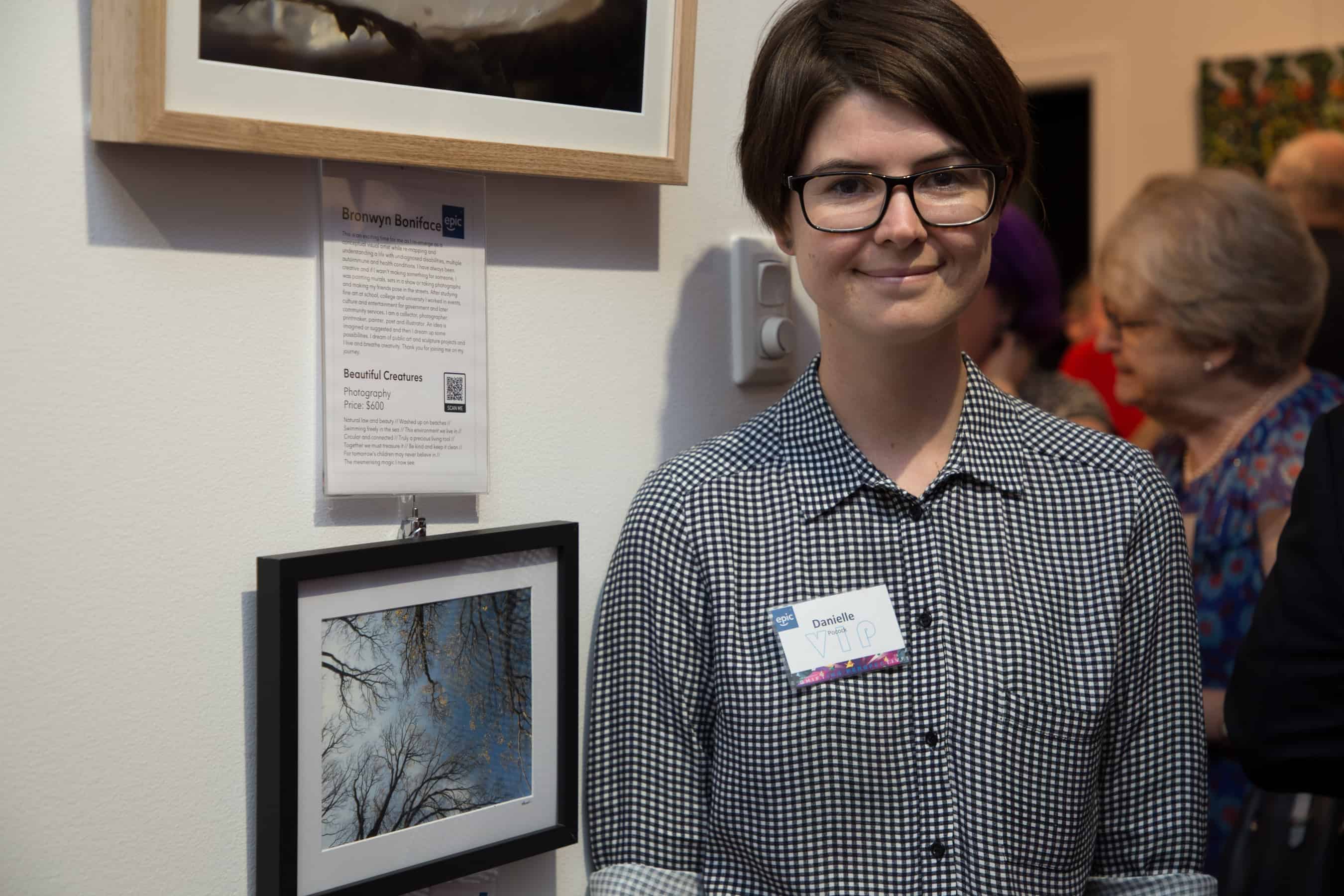 Artist Danielle stands next to her photograph
